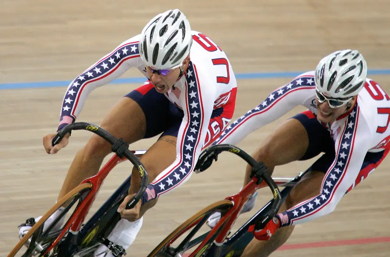 Dwóch kolarzy w strojach USA ściga się na torze rowerowym.