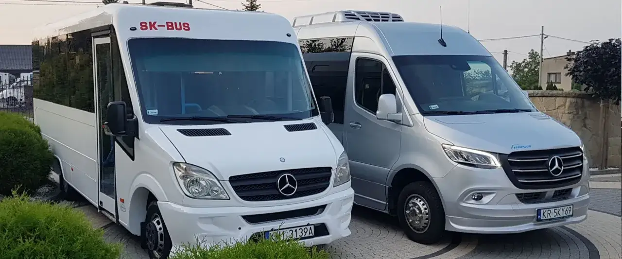 Dwa busy, biały SK-BUS i srebrny Mercedes, gotowe do podróży z Krakowa do Bochni.