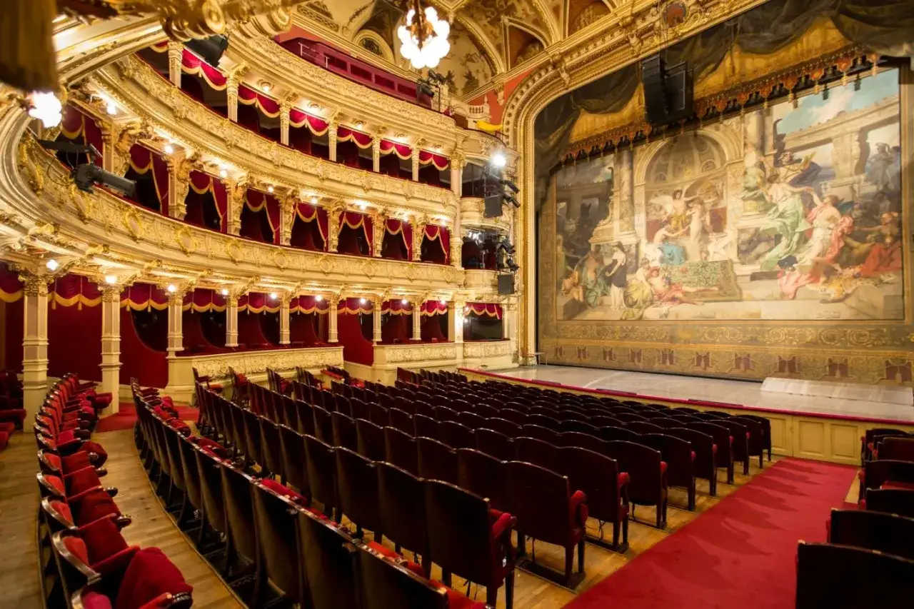 Elegancka sala teatralna z czerwonymi fotelami i bogato zdobioną sceną. Idealne miejsce, by sprawdzić, na co warto iść do teatru w Krakowie.