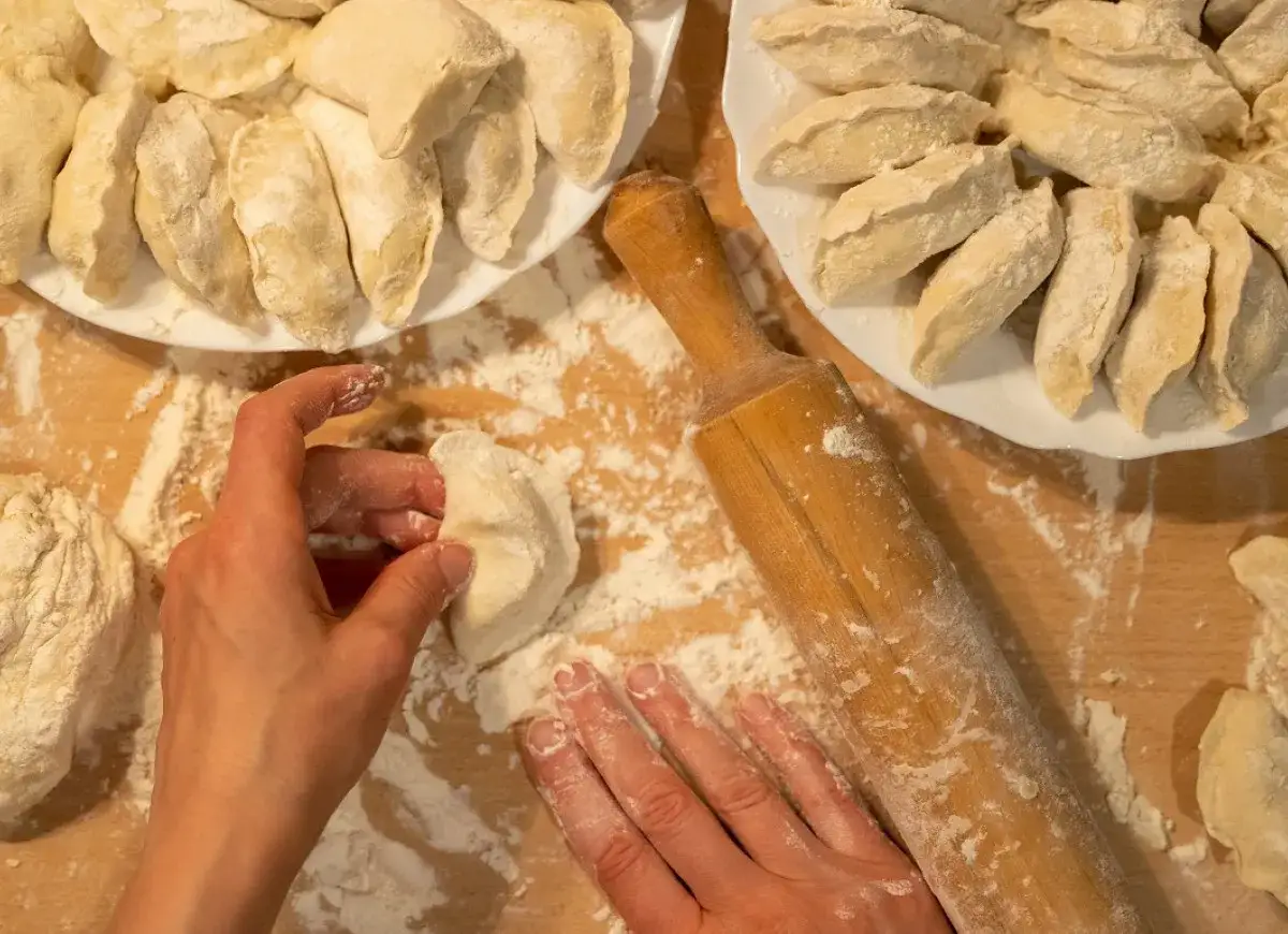 Ręcznie lepione pierogi na drewnianej desce. Zastanawiasz się, ile wyjdzie pierogów z pół kilograma mąki?
