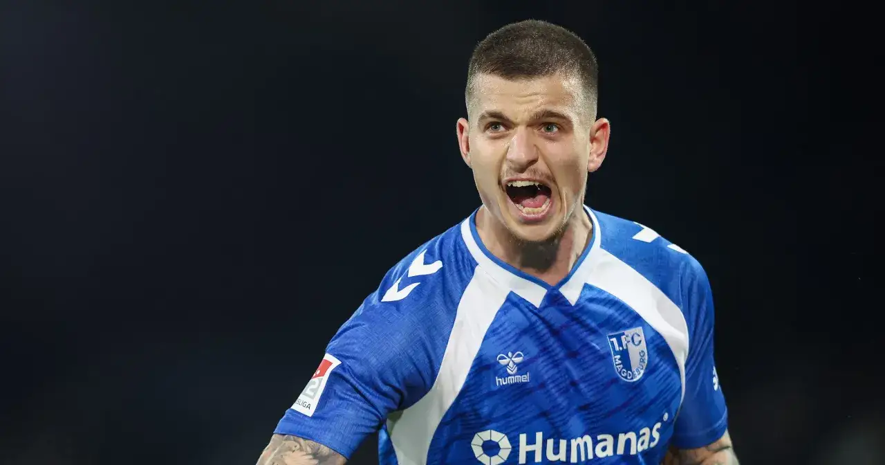 Piłkarz w niebieskiej koszulce z białymi wstawkami, krzyczący z radości. Może to być jeden z najlepszych bundes liga strzelcy.