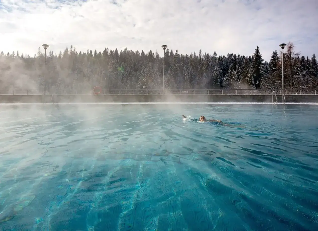 Kąpiel w basenie termalnym w Bukowinie Tatrzańskiej, gdy wok&oacute;ł widać śnieg i parę unoszącą się nad wodą.