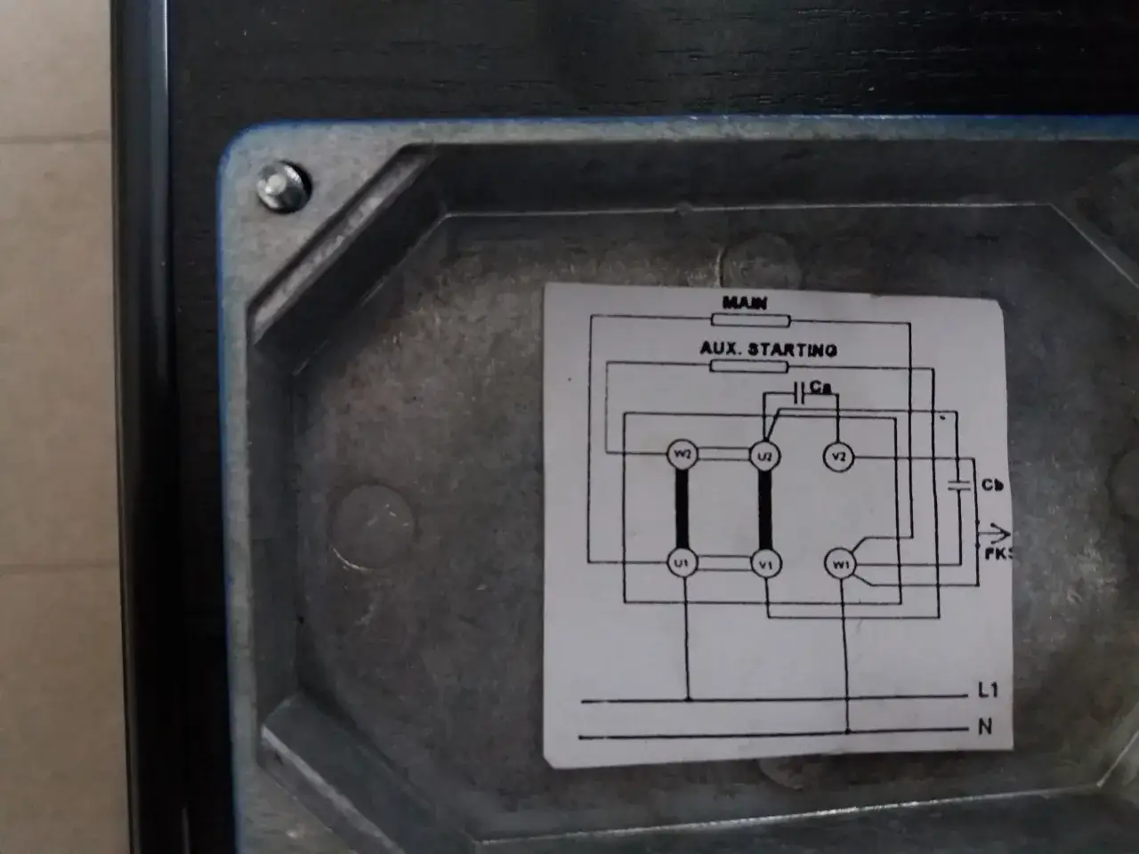 Schemat pokazuje, jak podłączyć kondensator rozruchowy do silnika. Widać połączenia zasilania L1 i N, uzwojeń głównych i pomocniczych.
