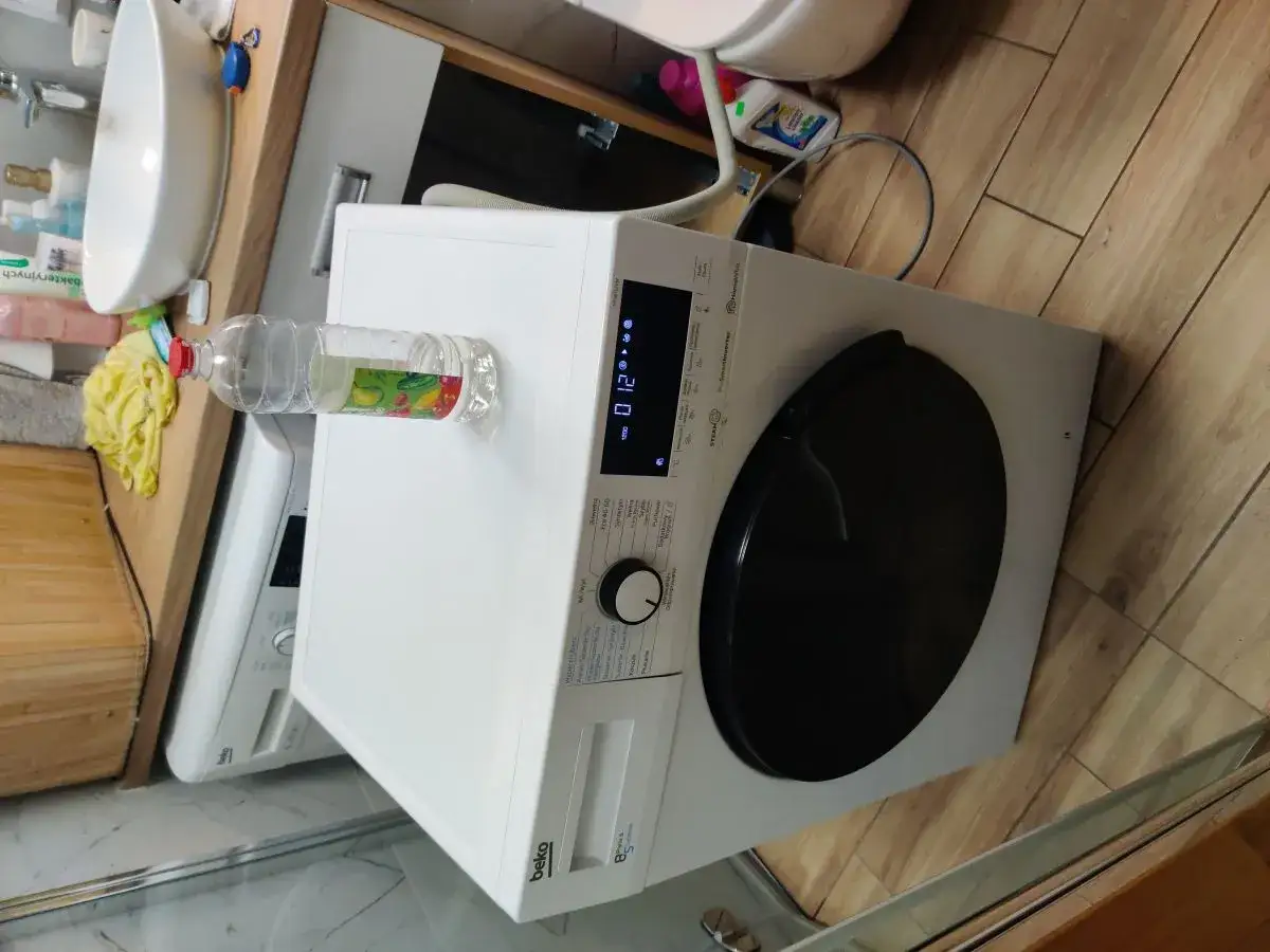 Beko pralka stoi w łazience, obok niej butelka z płynem. Czy pralki Beko są awaryjne? Zobaczymy.