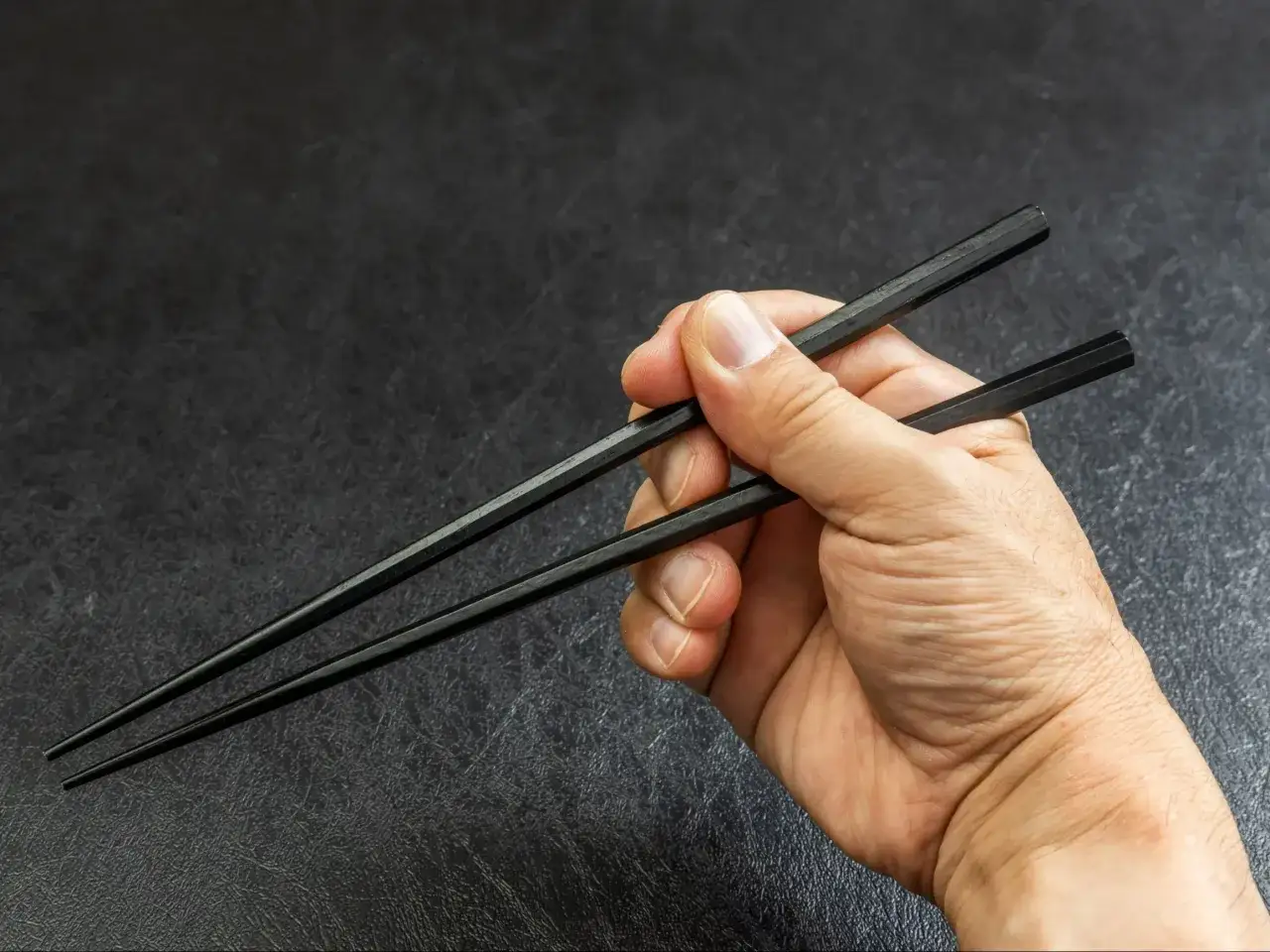 osoba jedząca ramen pałeczkami z uśmiechem