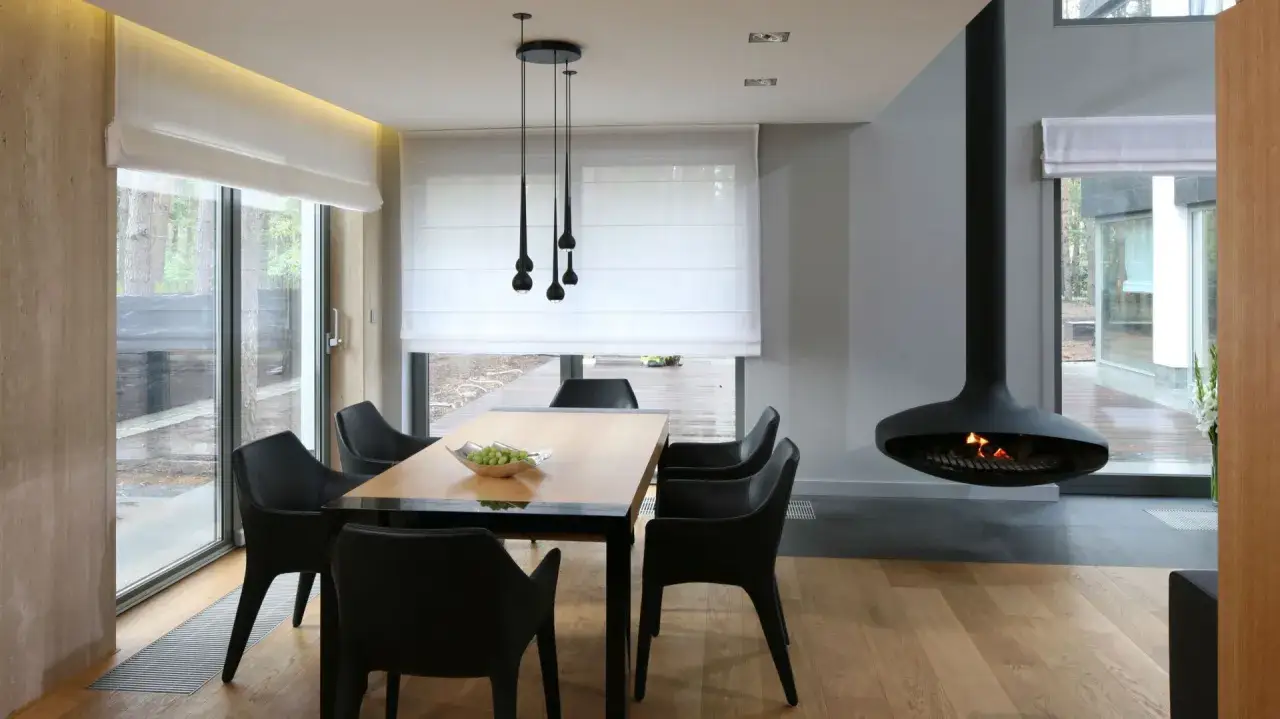 Nowoczesna lampa do jadalni nad stołem, otoczona czarnymi krzesłami i kominkiem wiszącym.