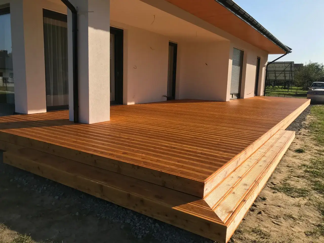 Nowy, drewniany taras z szerokimi schodami. Idealne rozwiązanie, by tanio wyłożyć taras i cieszyć się latem.