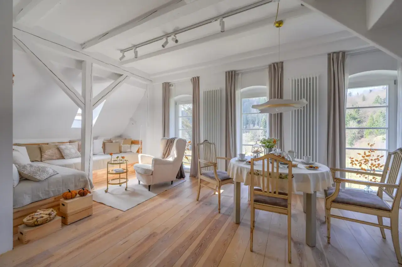 Przytulne trzy morza apartamenty pod Tr&oacute;jmorskim Wierchem. Jasne wnętrze z drewnianymi belkami, wygodną sofą i stołem do posiłk&oacute;w.