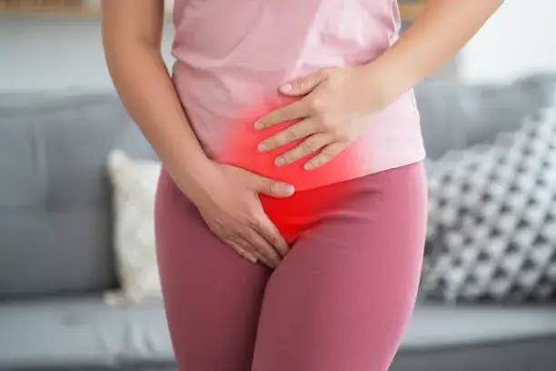 kobieta cierpiąca na b&oacute;l menstruacyjny, trzymająca się za brzuch
