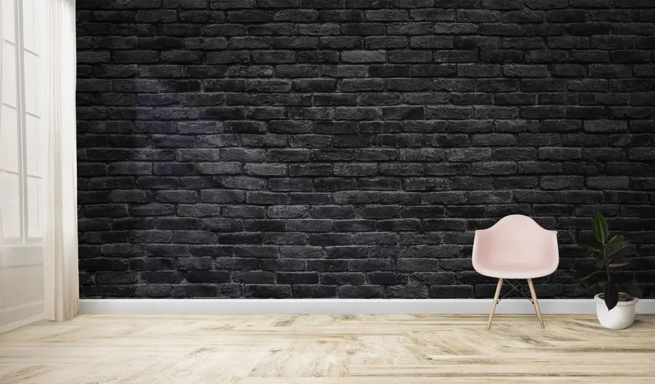 Minimalistyczne wnętrze z tapetą czarna cegła, jasną podłogą, różowym fotelem i rośliną w doniczce.