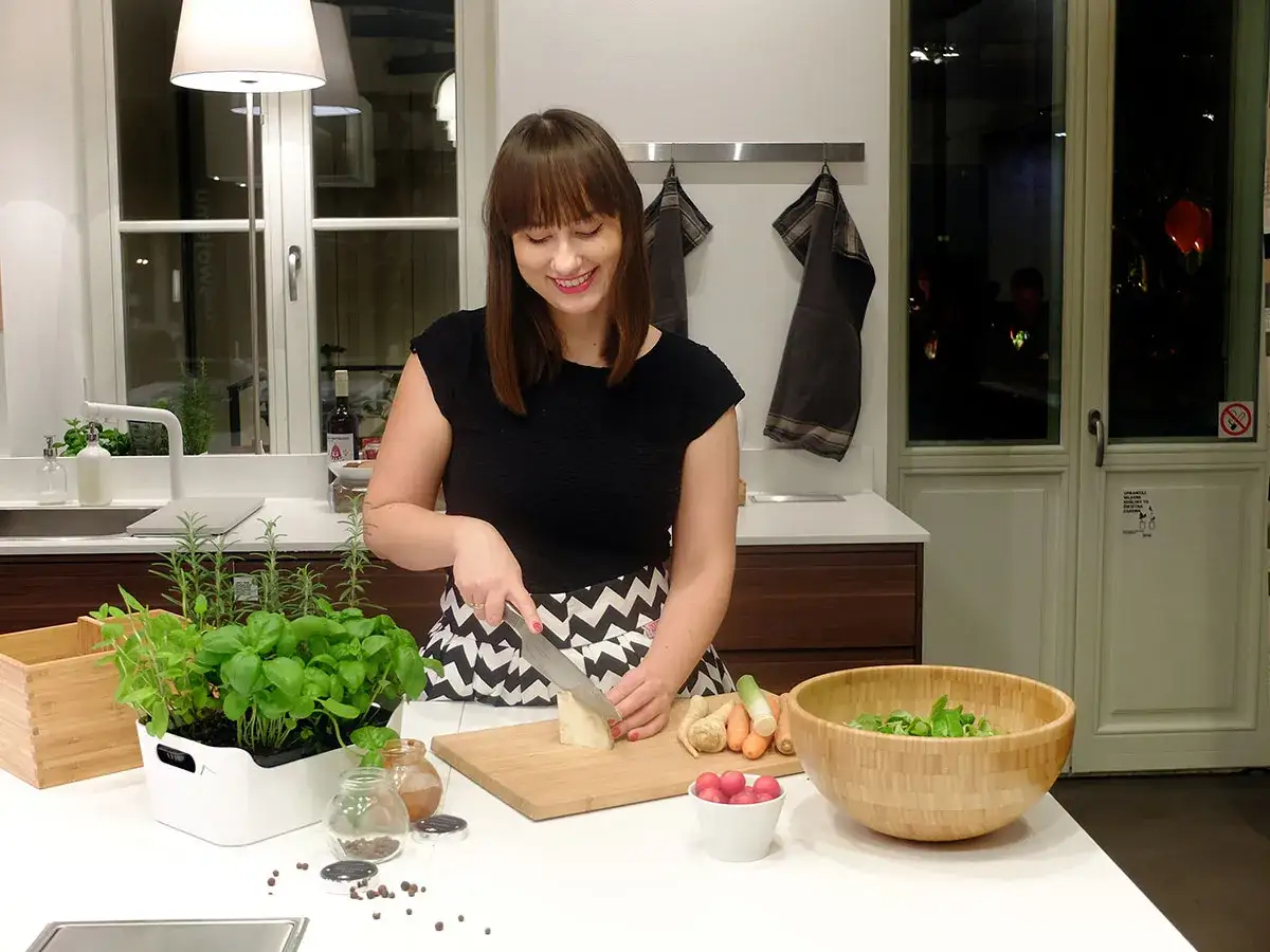 Kobieta kroi ser na desce, obok świeże zioła i warzywa. Idealne składniki, co można ugotować na szybko.