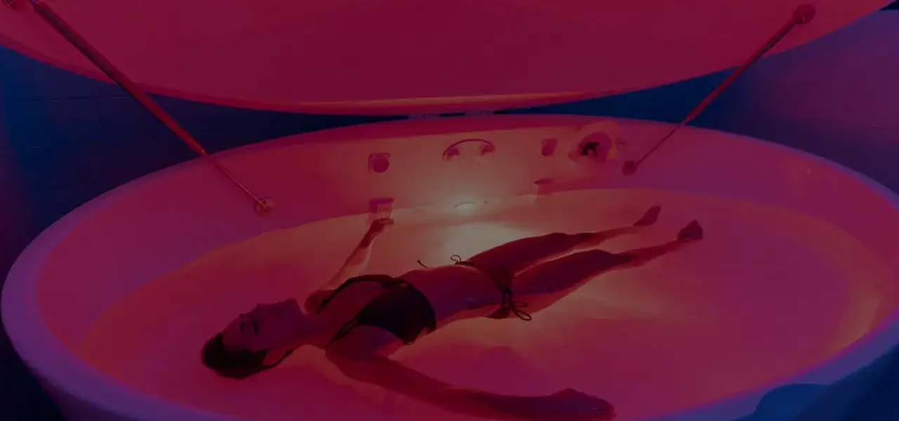 Kobieta w bikini unosi się na wodzie w kapsule floatingowej, doświadczając głębokiego relaksu.