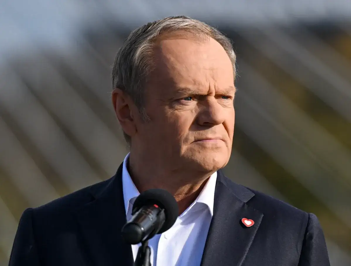 Donald Tusk w garniturze, z przypinką w kształcie serca. Choć nie widać tego na zdjęciu, jego wzrost to 183 cm.