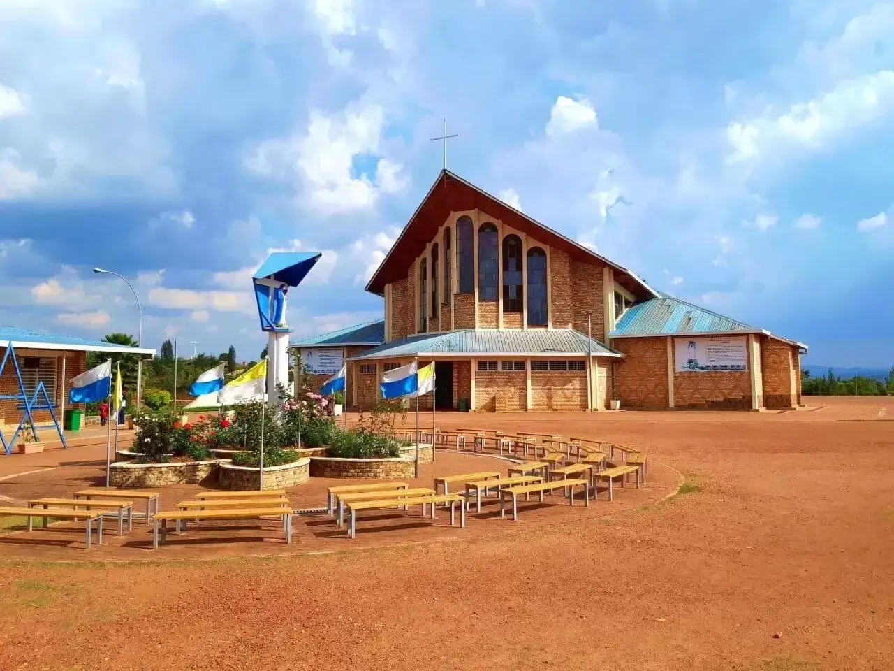 Kości&oacute;ł w kraju z Kigali, z ławkami i pomnikiem Matki Bożej.