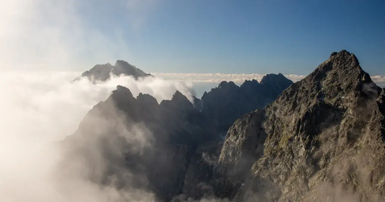 Widok na skaliste szczyty Tatr Wysokich, mgła otula zbocza, zapowiada trudne wejście na Gerlach.