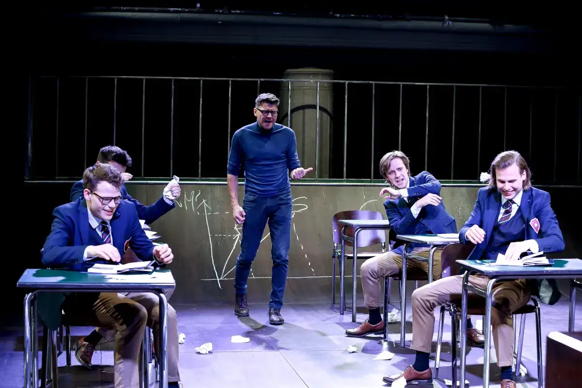 Nauczyciel przemawia do uczniów w szkolnej ławce. Scena z teatru 