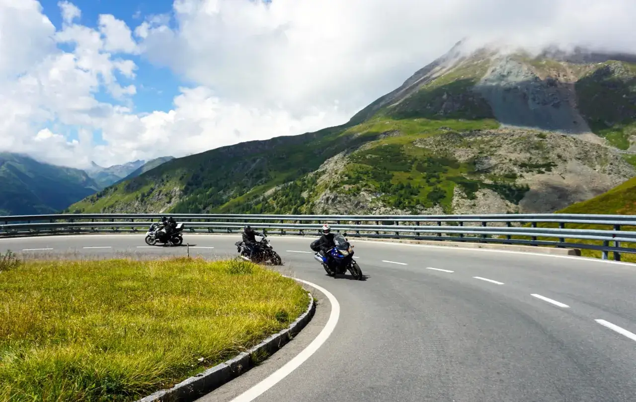 Motocykliści przemierzają malownicze trasy motocyklowe w Austrii, pokonując zakręty g&oacute;rskiej drogi na tle spektakularnych krajobraz&oacute;w.