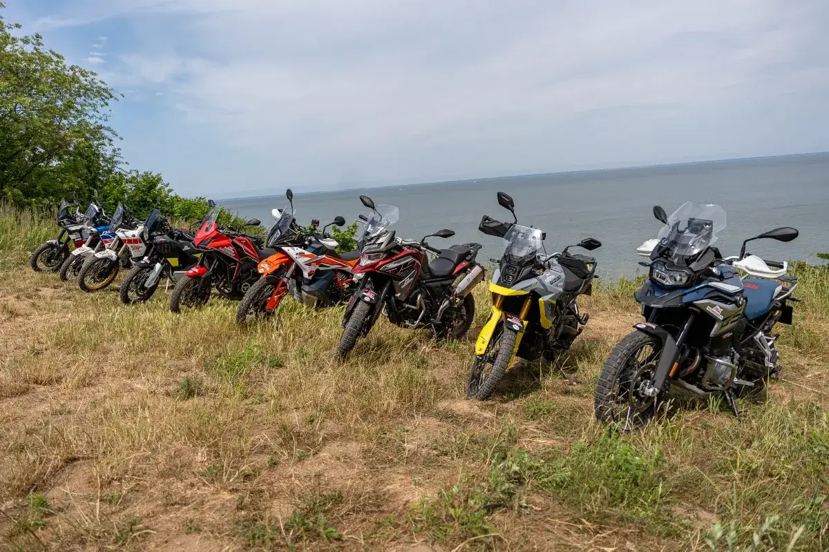 Rząd motocykli typu adventure gotowych na wyprawę nad wodę.