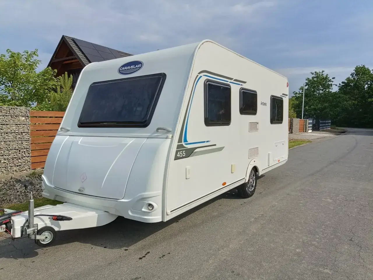 Biała przyczepa kempingowa Caravelair Antares 455 zaparkowana na drodze, gotowa na wakacyjne podr&oacute;że.