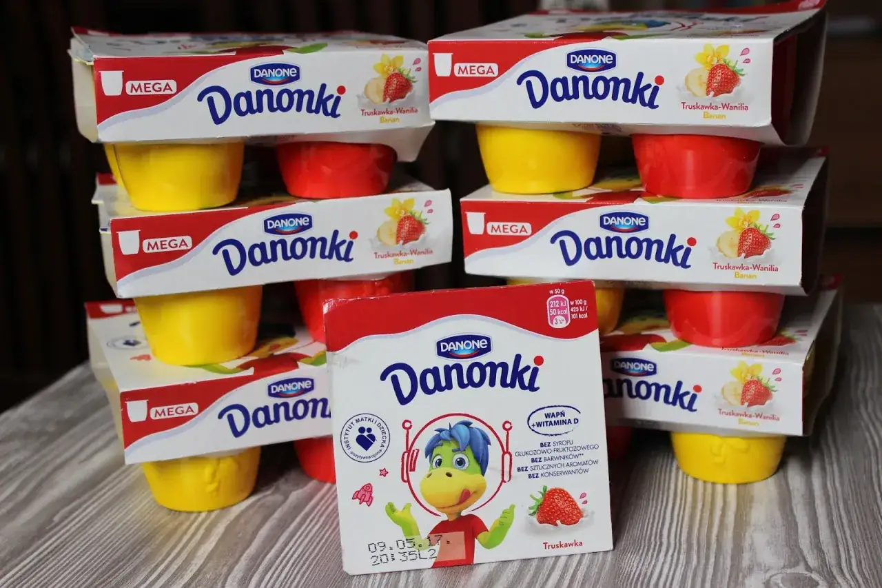 Stosik jogurtów Danonki dla dzieci o smaku truskawka-wanilia-banan. Kolorowe kubeczki i opakowania zachęcają do jedzenia.