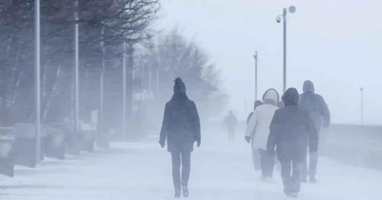 Ludzie idący w zamieci śnieżnej, chroniący się przed zimnem i chorobą układu oddechowego.