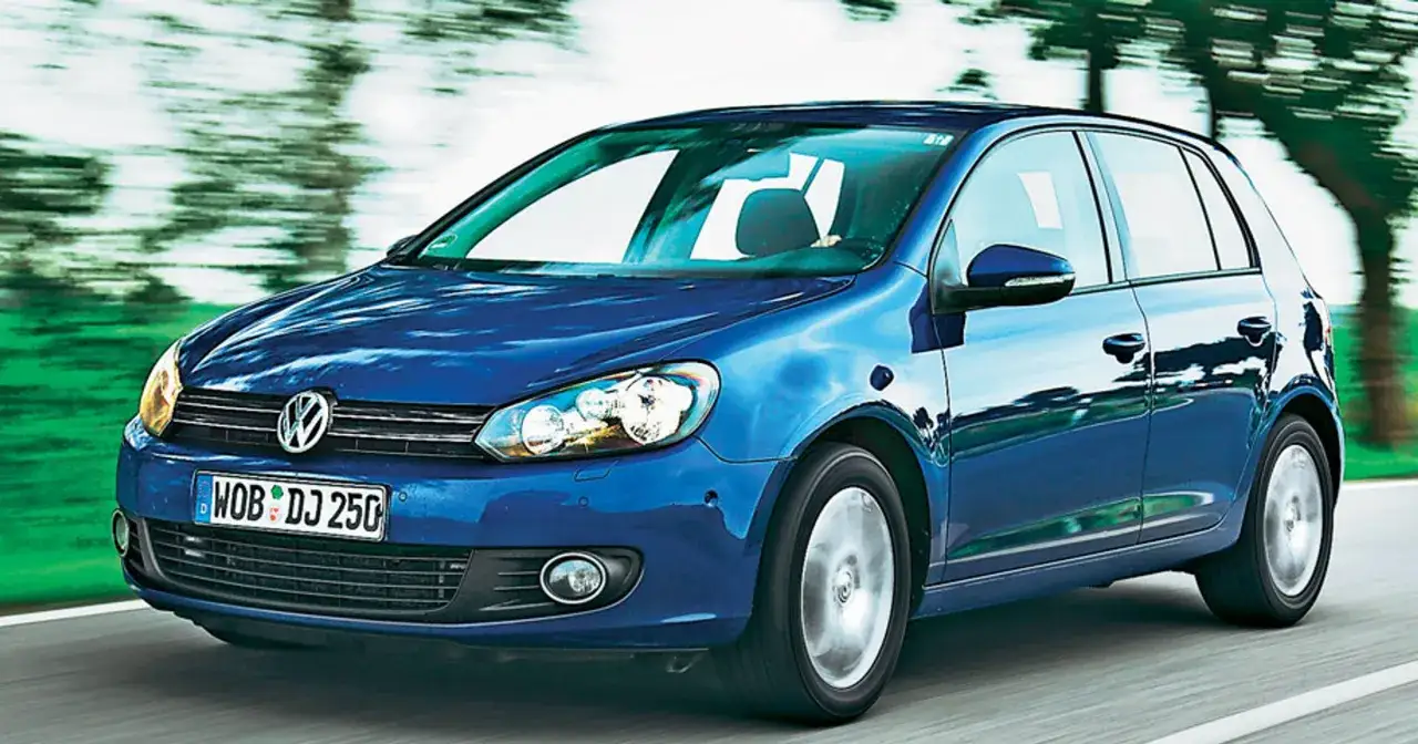 Niebieski Volkswagen Golf 6 R pędzi po drodze, otoczony rozmytym tłem zieleni i drzew.