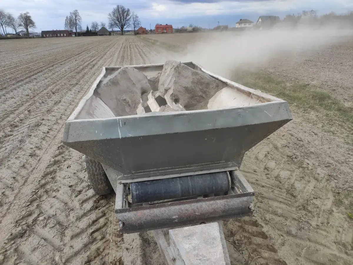 Rozsiewacz wapna na polu. Wapnowanie gleby poprawia jej strukturę i żyzność, co daje lepsze plony.