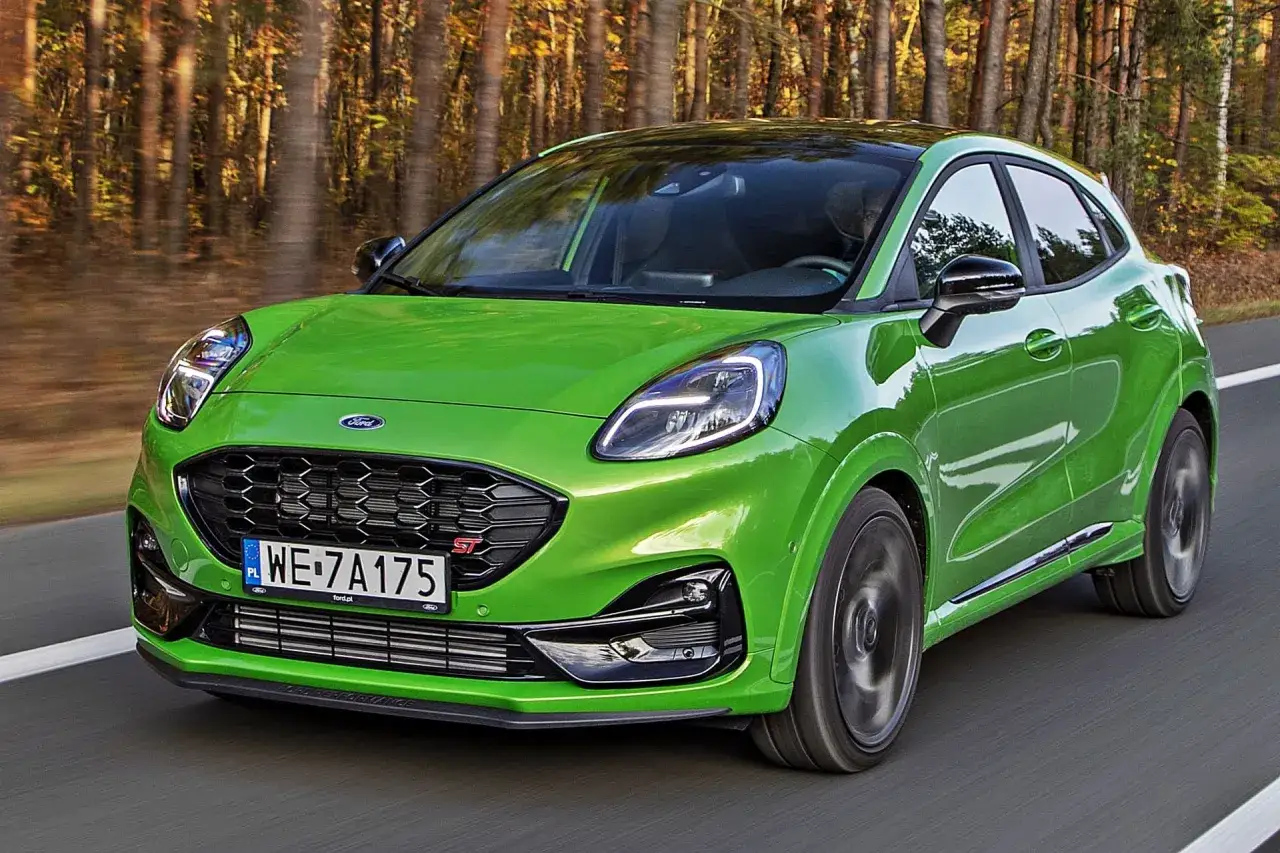 Zielony Ford Puma ST w ruchu, zgrabne ford puma wymiary pozwalają na zwinne manewry w otoczeniu jesiennego lasu.