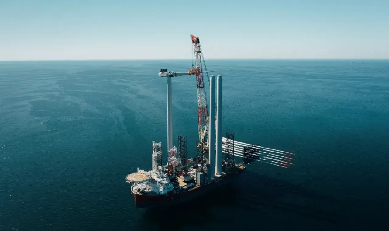 Statek instaluje turbinę wiatrową na morzu. Wiele takich instalacji buduje się, by odpowiedzieć na pytanie: ile jest wiatrak&oacute;w w Polsce.