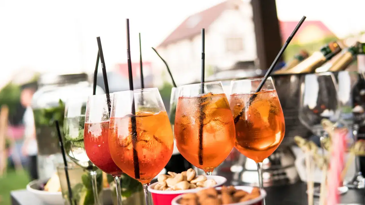Orzeźwiające drinki z Campari i Aperol Spritz, z lodem i plasterkami pomarańczy, gotowe na letnie przyjęcie.