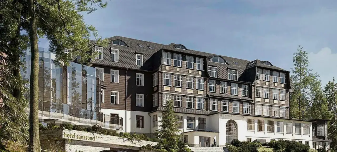 Elegancki hotel Sanssouci Karpacz z nowoczesną szklaną fasadą i tradycyjną architekturą, otoczony zielenią.