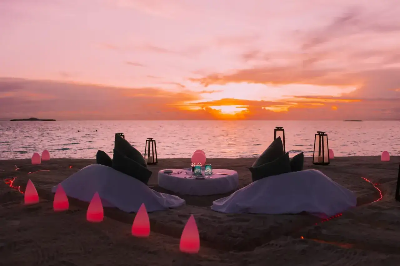 Romantyczna kolacja na plaży Malediwów o zachodzie słońca. Idealny czas, kiedy najlepiej jechać na Malediwy, by doświadczyć takich widoków.