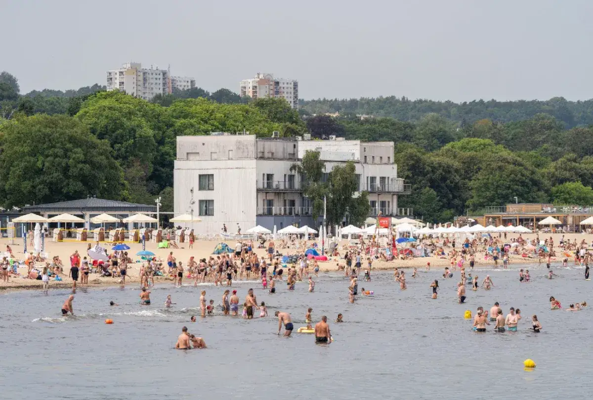 Tłumy ludzi odpoczywają na plaży i kąpią się w morzu. Idealne miejsce, gdzie nad Bałtyk.