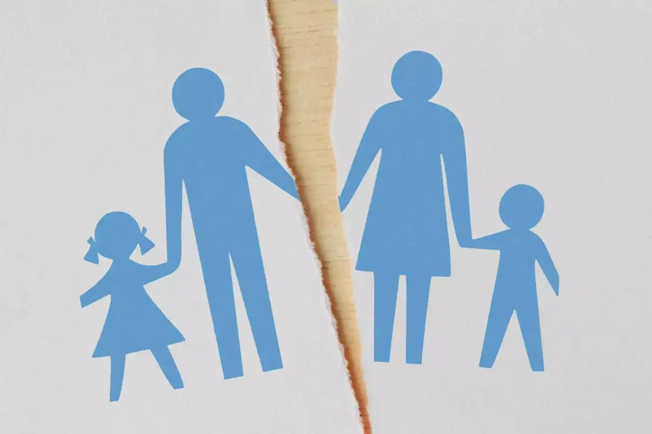 Rozwód a dzieci: rozdarty papier symbolizuje rozpad rodziny, gdzie rodzice trzymają za ręce swoje pociechy, ale ich ścieżki się rozchodzą.