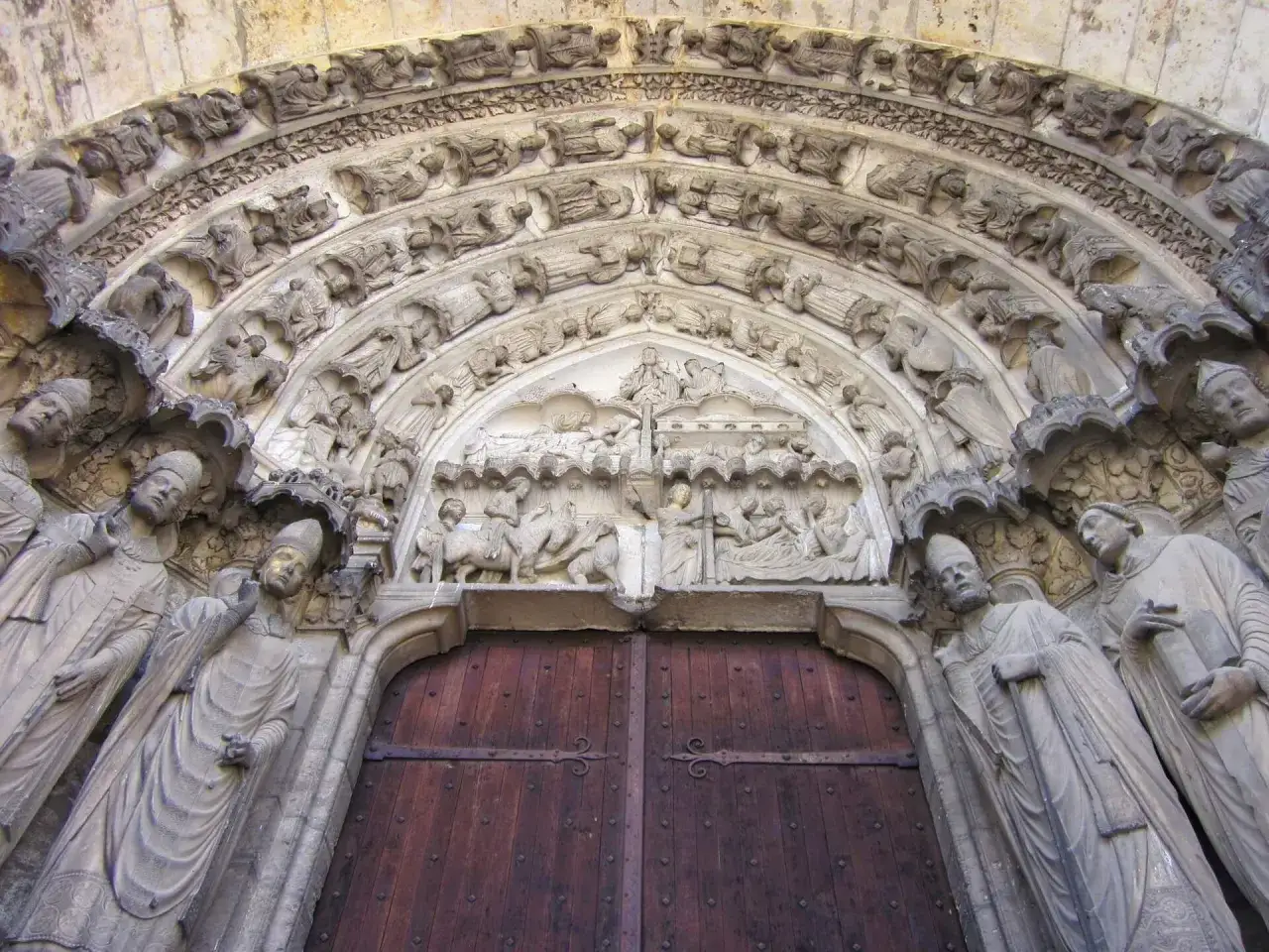 Kamienne rzeźby zdobią portal katedry w Chartres, przedstawiając sceny biblijne i świętych.
