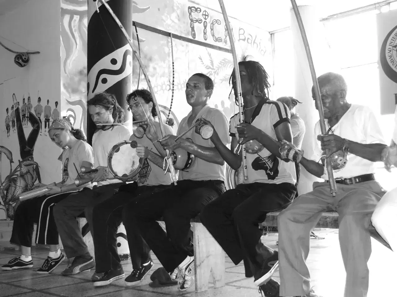 Grupa ludzi gra na instrumentach i śpiewa, tworząc rytm dla capoeira. To właśnie capoeira co to za sztuka walki i taniec.