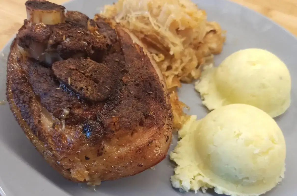 Soczysta golonka z chrupiącą skórką, podana z kapustą i purée. Dowiedz się, ile gotować golonkę w szybkowarze, by była idealna!