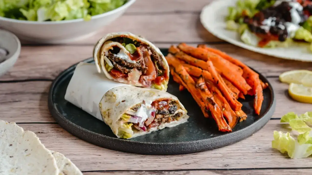 Pyszny durum kebab z soczystym mięsem, warzywami i sosem, podany z chrupiącymi frytkami z batatów. Idealna propozycja na szybki i sycący posiłek.