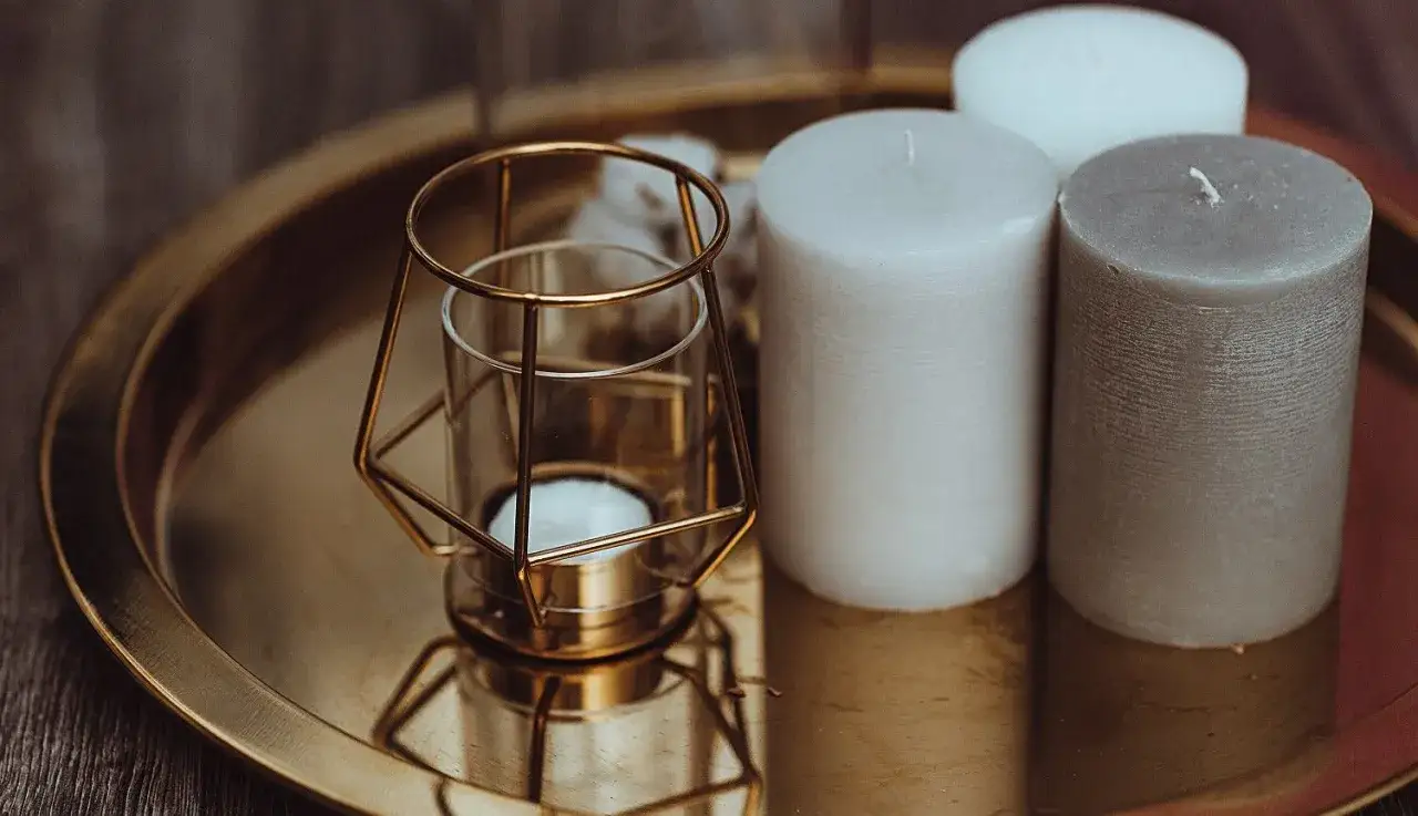 Złota taca dekoracyjna z geometrycznym świecznikiem i trzema świecami tworzy nastrojowe aranżacje.