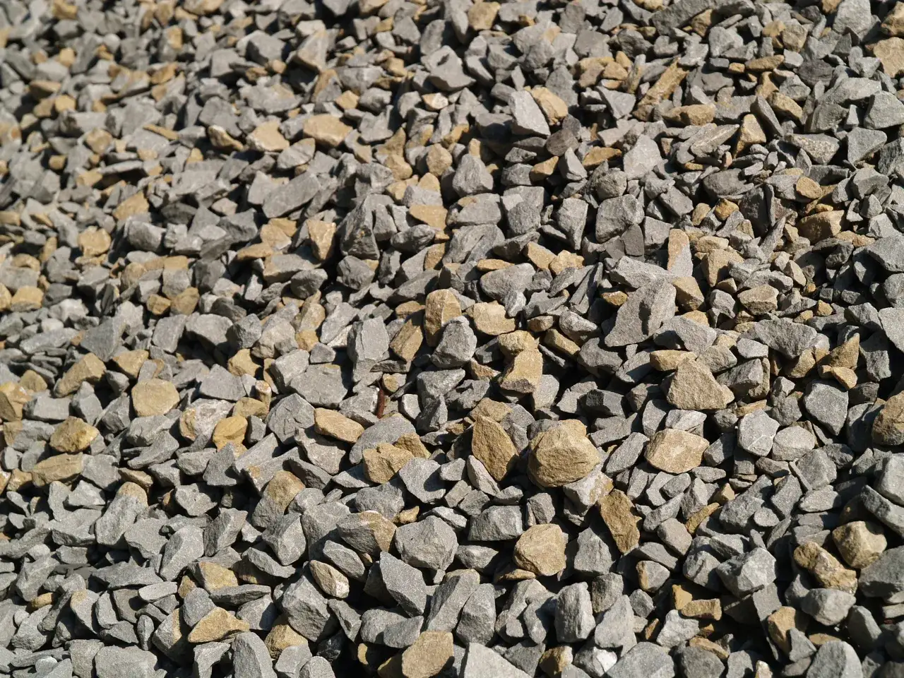 Sypki tłuczeń, szary i żółtawy, tworzy teksturę. Zastanawiasz się, ile kosztuje tłuczeń na podjazd?