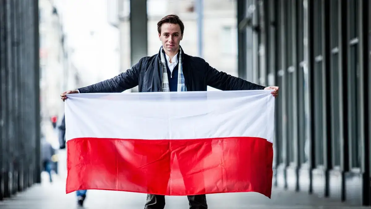Krzysztof Bosak na tle polskiej flagi