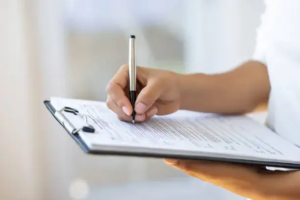osoba wypełniająca formularz, biurko z dokumentami, długopis