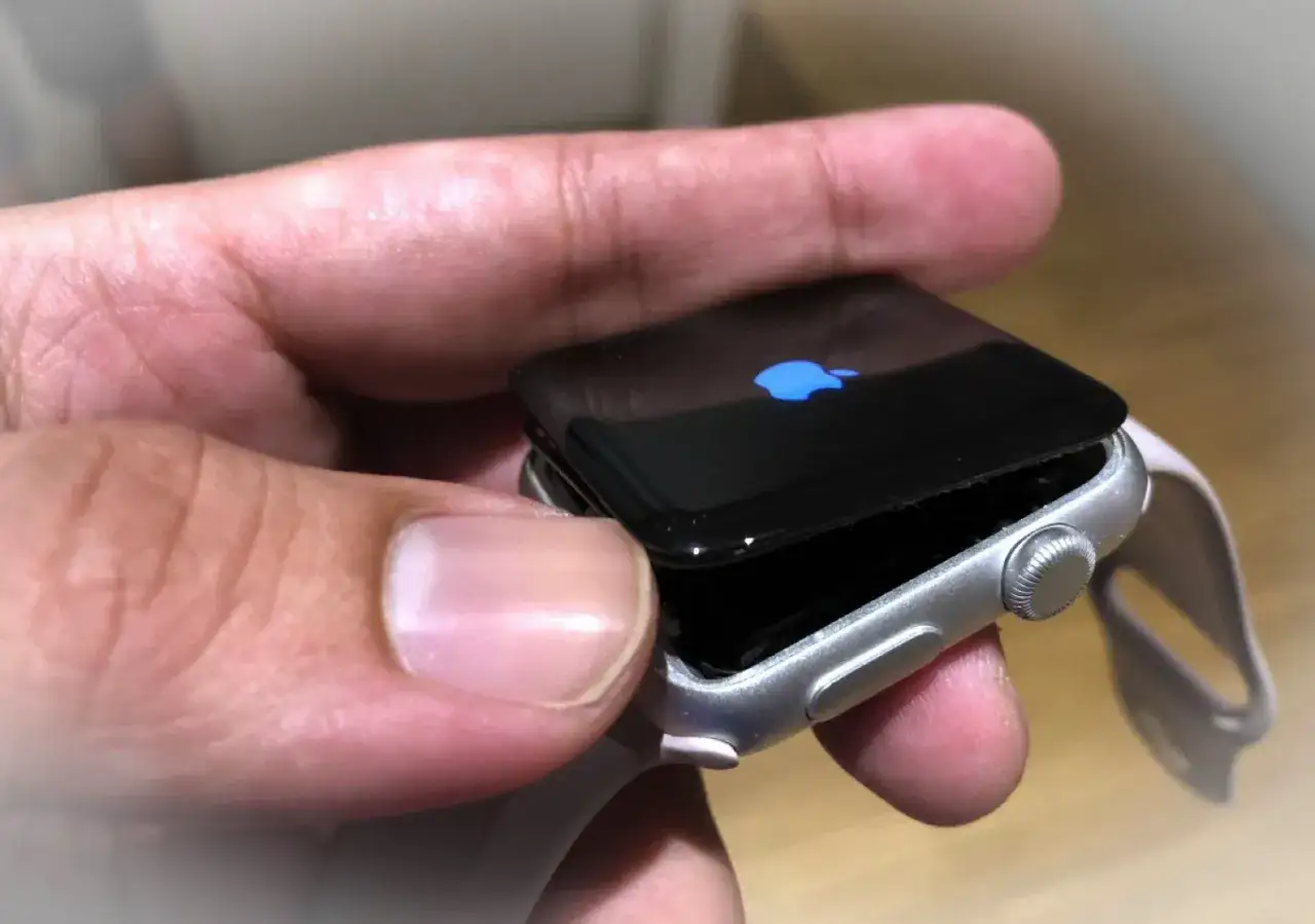 Uszkodzony smartwatch, kt&oacute;rego wyświetlacz nie działa. Widać niebieskie logo Apple.