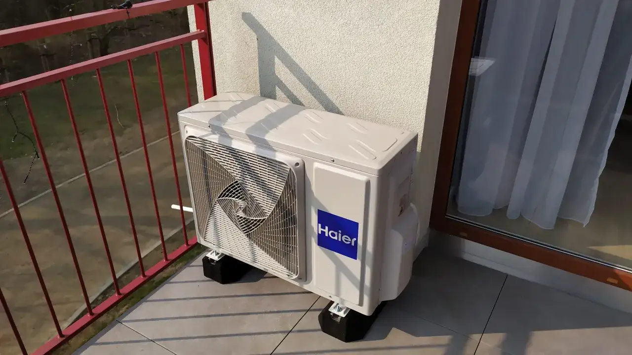 Jednostka zewnętrzna klimatyzacji Haier na balkonie bloku, zapewniająca komfortowe chłodzenie.