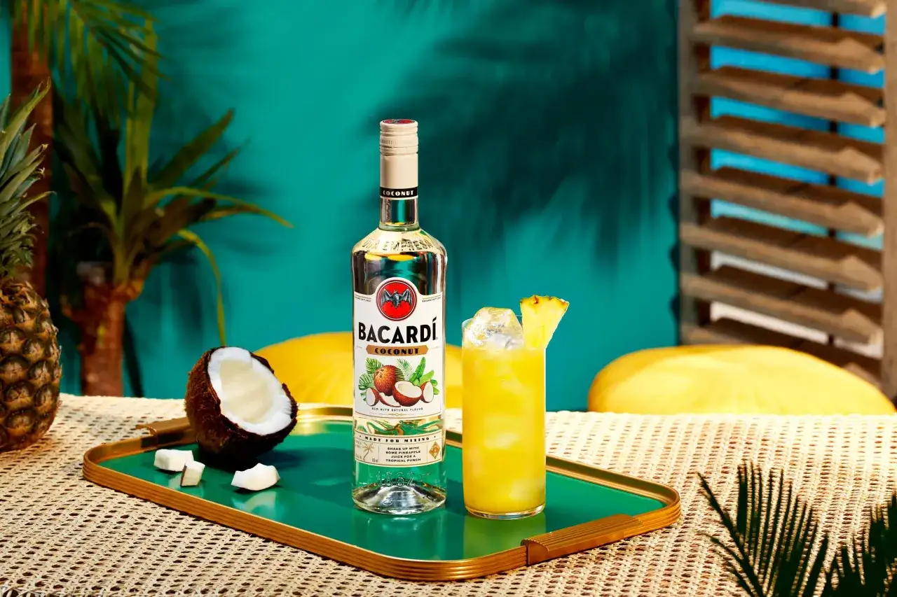 Butelka Bacardi Coconut, kokos, ananas i drink z ananasem na tropikalnym tle. Idealne składniki na letnie bacardi kokosowe drinki.