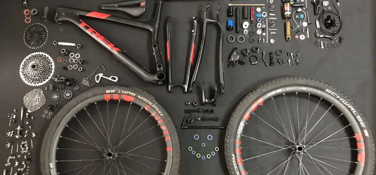 Rozłożony rower g&oacute;rski Trek. Amortyzator w rowerze nie ugina się, leży obok ramy, k&oacute;ł i innych części.