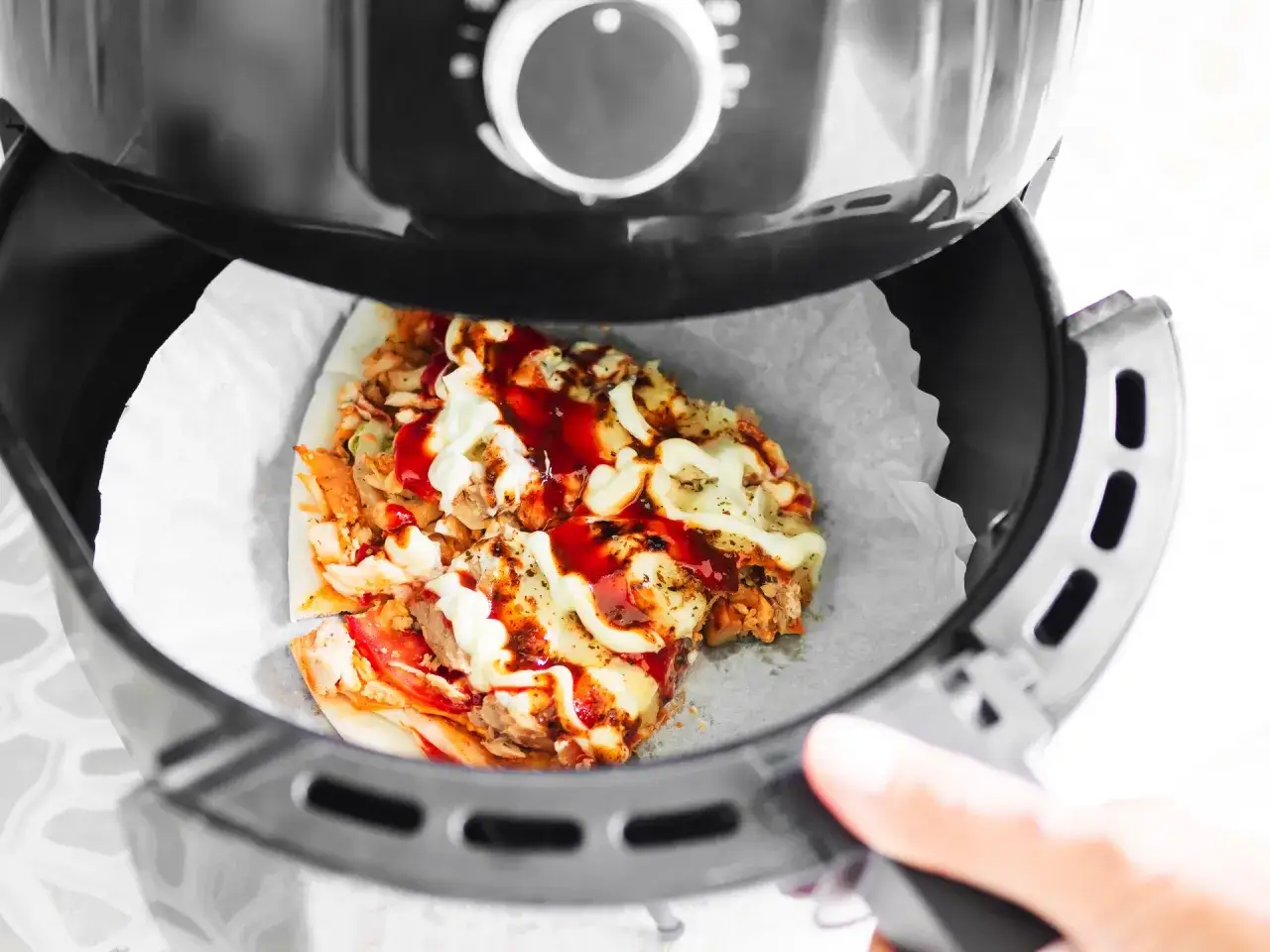 Jak odgrzać pizzę w frytkownicy beztłuszczowej? Kawałek pizzy z serem i sosami w środku.