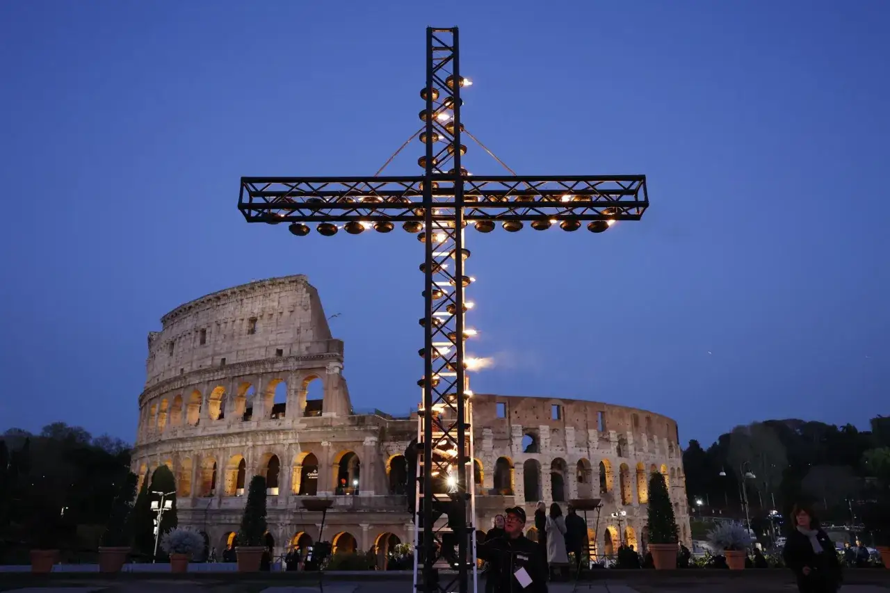 Wielki krzyż z płonącymi pochodniami przed Koloseum w Rzymie, kiedy jest Droga Krzyżowa.