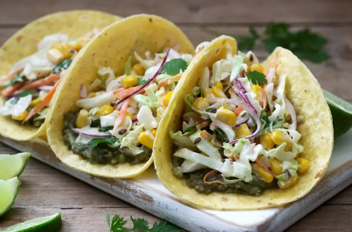 Jak zrobić taco wegetariańskie: pyszne, kolorowe taco z awokado, kukurydzą, kapustą i marchewką.