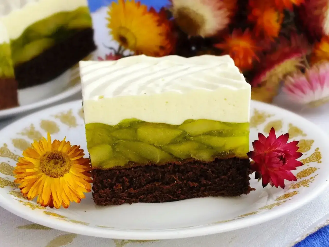 Pyszny jabłecznik na biszkopcie z warstwą zielonej galaretki z jabłkami i bitą śmietaną.